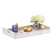 A white-washed pine wood room service tray with cupcakes and flowers on it.