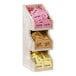 A Cal-Mil Newport white-washed wood 3-tier condiment organizer on a counter with several packets in it.