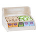 A Cal-Mil white-washed pine wood condiment organizer with different types of tea packets on a counter.