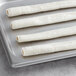 A tray of white rolled up Backyard Pro Butcher Series Collagen Sausage Casings.