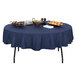 A Correll 60" round folding table with food on it and a blue tablecloth.