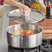 A Vigor stainless steel stock pot with a cover cooking a lobster.