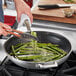 A person using a Vigor stainless steel non-stick fry pan to cook asparagus.
