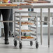A woman using a Regency sheet pan rack to store trays of pastries in a school kitchen.