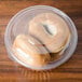 A Dart clear plastic bowl with a dome lid holding two bagels.