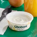A bowl of Chobani Non-Fat Vanilla Greek Yogurt with a spoon and a glass of orange juice.