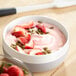 A bowl of Yoplait strawberry yogurt with strawberries on top.