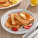 A plate of Krusteaz whole grain French toast with butter, syrup, and strawberries.