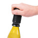 A hand using a black Franmara wine saver to seal a bottle.