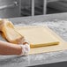 A person rolling out dough on a table using Isigny Sainte-Mere unsalted lamination butter.