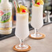 A close up of a Zing Zang Pina Colada Mix can with a glass of white liquid and fruit on it.