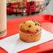 An Otis Spunkmeyer chocolate chip muffin on a napkin on a red tray.