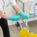 A man wearing green Ansell AlphaTec Solvex gloves is cleaning the floor with a mop.