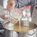 A person pouring milk into a pot of liquid.