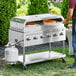 A person cooking pizzas on a Backyard Pro stainless steel grill.