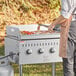 A man cooking bacon on a Backyard Pro outdoor griddle on a table.