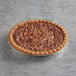 A Chef Pierre Southern Pecan Pie in a pie tin on a table.