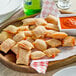 A plate of Totino's Pepperoni Pizza Rolls with a bowl of red sauce on a table.