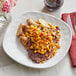 A plate of food with Simplot flame-roasted sweet corn and peppers, steak, and a fork and knife.