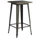 A Lancaster Table & Seating black metal bar height table with a distressed gold top.