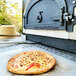 A cheese pizza baking in a Chicago Brick Oven Tailgater outdoor pizza oven.