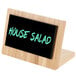 A bamboo framed write on board with black writing that says "house salad" on a table.