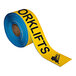 A roll of yellow tape with black text reading "Watch Out For Forklifts"