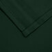 A close up of a hunter green rectangular cloth table cover with a hemmed corner.