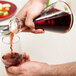 A person pouring red wine from a Stolzle Pisa carafe into a glass.