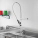 A stainless steel sink with a Regency deck-mounted pre-rinse faucet and hose.