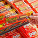 A hand holding a package of REESE'S King Size Milk Chocolate Peanut Butter Cups.