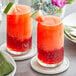 Two glasses of red watermelon juice with cucumber on a plate.
