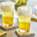 Two glasses of yellow Fanale pineapple drinks on coasters.