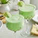 Two glasses of green Fanale Honeydew powder drinks with a slice of apple on the rim.