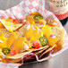 A bowl of nachos with Real Fresh Sharp Cheddar Cheese Sauce and jalapenos.