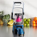 A Waring commercial blender with a blue lid on top filled with fruit.