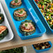 A blue Cambro market pan filled with food on a table.