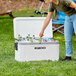 A woman putting bottles in a white Igloo Marine cooler.