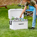 A woman putting beer bottles in a white Igloo Marine cooler.