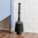 A black Lavex toilet plunger on a wood floor.