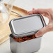 A hand holding a Matfer Bourgeat stainless steel container lid filled with spices.