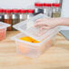 A hand using a Cambro translucent polypropylene lid to cover a plastic food container.