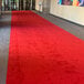 A red FloorEXP carpet runner on the floor in a hallway.