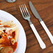 A plate of pasta with a WNA Comet Reflections Duet ivory plastic fork on a table.