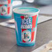 A blue and white ICEE cup with a blue and white label filled with ice cream and a wooden spoon.