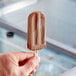 A hand holding a JonnyPops Chocolate Fudge and Oat Milk Popsicle