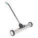 A long metal Vestil floor sweeper with wheels and a handle.