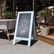 A Flash Furniture vintage robin blue wooden A-frame chalkboard with text on it.