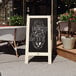 A Flash Furniture vintage white wood A-frame chalkboard with a menu on the sidewalk.