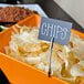 An American Metalcraft double-sided flexible sign clip holding a sign in a bowl of chips on a table.